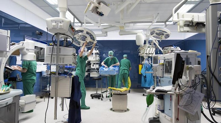 OP-Personal und ein OP-Reinigungsteam arbeiten nach einer Operation in einem Operationssaal. Foto: Christian Charisius/dpa/Symbolbild