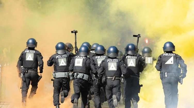 Polizisten laufen vor dem Stadion durch den Nebel von Pyrotechnik. Foto: Sebastian Kahnert/dpa/Archivbild