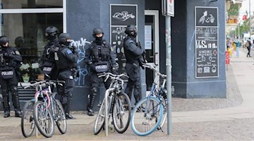 Polizisten stehen in Leipzig an einer Hausecke. Foto: Tobias Junghannß/dpa-Zentralbild/dpa