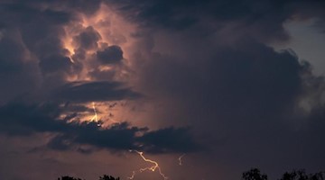 Ein Blitz hellt hinter dunklen Wolken auf. Foto: Fabian Sommer/dpa