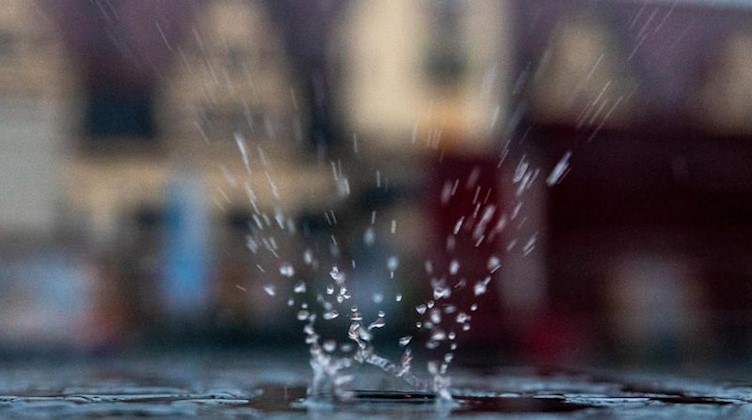 Ein Regentropfen fällt auf eine Pfütze auf einem Tisch im Außenbereich eines Restaurants. Foto: Hendrik Schmidt/dpa-Zentralbild/dpa