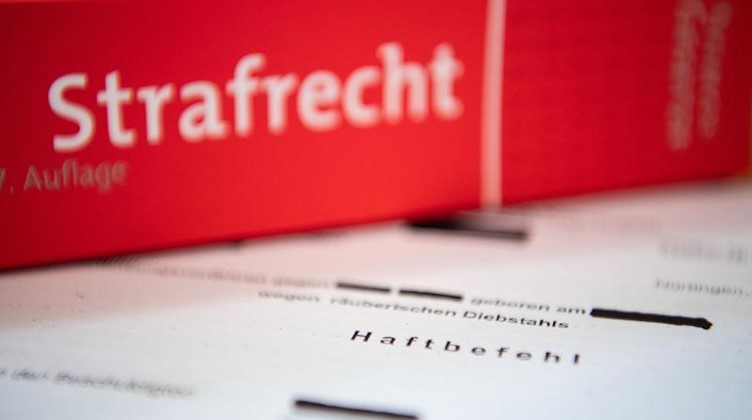 Eine Abschrift eines Haftbefehls liegt mit einem Strafrecht-Buch auf dem Tisch. Foto: Tom Weller/dpa/Illustration