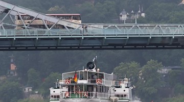 Bei regnerisch-grauem Wetter fährt ein Dampfer der Sächsischen Dampfschiffahrt unter der Brücke Blaues Wunder entlang, einem Dresdner Wahrzeichen. Foto: Matthias Rietschel/dpa-Zentralbild/dpa
