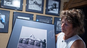 Gabriela Ender hält eine der Fotografien für die Ausstellung "Akt und Landschaft“ in der Hand. Foto: Jens Büttner/dpa-Zentralbild/dpa