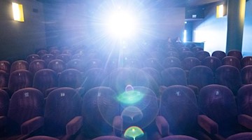 Der Filmprojektor leuchtet im Kinosaal. Foto: Julian Stratenschulte/dpa/Symbolbild