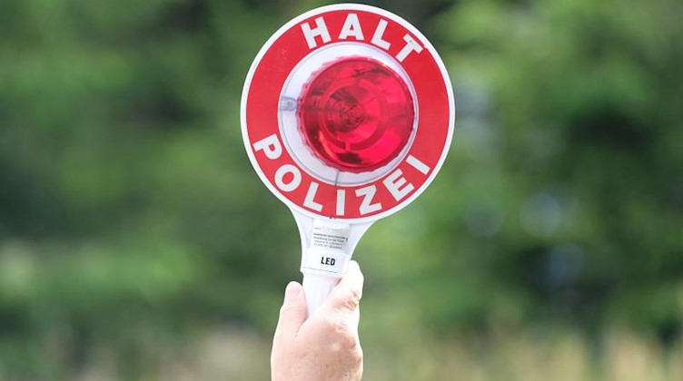 Eine Polizistin hält eine rote Winkerkelle in die Höhe. Foto: Sebastian Willnow/zb/dpa/Symbolbild