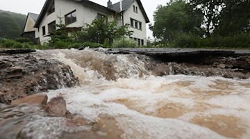 Wasser läuft bei Heimbach an einem Haus vorbei den Hang hinunter. Foto: Oliver Berg/dpa