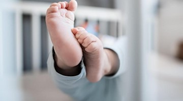 Die Füße eines Babys sind in einem Kinderbett zu sehen. Foto: Fabian Strauch/dpa/Archivbild