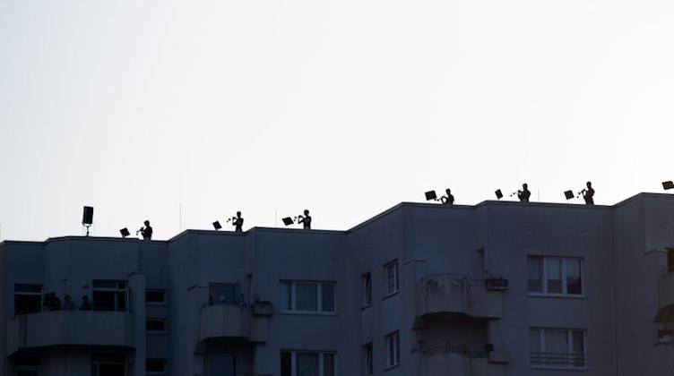 Musiker stehen auf dem Dach eines Hochhauses und spielen ihre Instrumente. Foto: Jonas Walzberg/dpa
