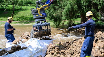 Einsatzkräfte des THW (Technisches Hilfswerk) beseitigen am Krippenbach Geröll. Foto: Robert Michael/dpa-Zentralbild/dpa