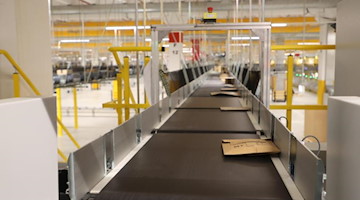 Amazon-Versandkartons liegen auf Transportbändern bei einem Probebetrieb in einer Logistikhalle. Foto: Bodo Schackow/dpa-zentralbild/dpa