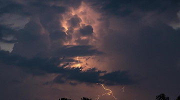 Ein Blitz hellt hinter dunklen Wolken auf. Foto: Fabian Sommer/dpa/Symbolbild