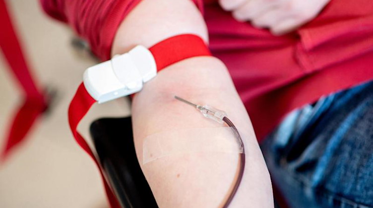 Blut läuft während einer Blutspende vom Arm einer Spenderin durch eine Nadel in einen Beutel. Foto: Hauke-Christian Dittrich/dpa/Symbolbild