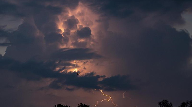 Ein Blitz hellt hinter dunklen Wolken auf. Foto: Fabian Sommer/dpa/Archivbild