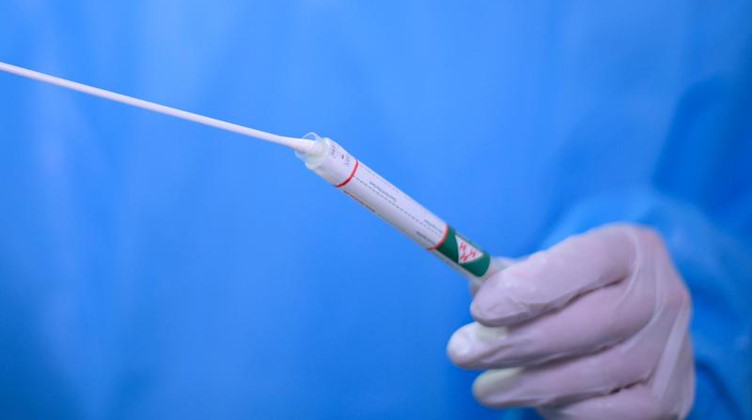 Ein Arzt hält einen Coronavirus-Test in den Händen. Foto: Robert Michael/dpa-Zentralbild/dpa/Symbolbild