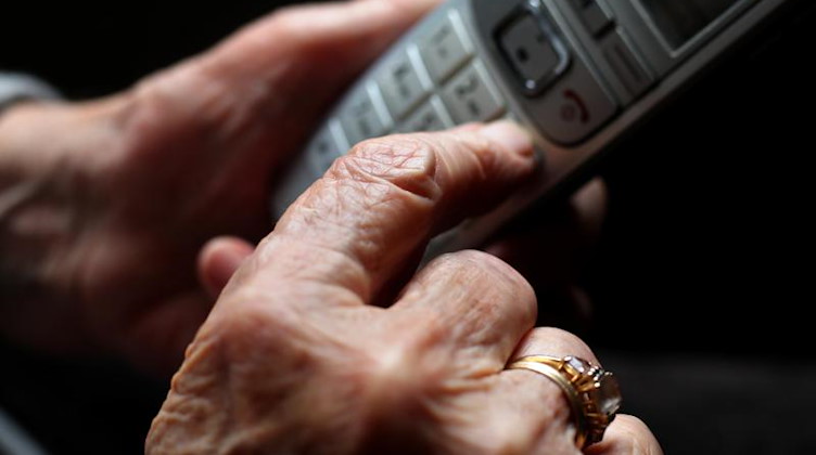 Eine ältere Frau tippt auf einem schnurlosen Festnetztelefon. Foto: Karl-Josef Hildenbrand/dpa/Symbolbild