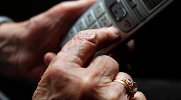 Eine ältere Frau tippt auf einem schnurlosen Festnetztelefon. Foto: Karl-Josef Hildenbrand/dpa/Symbolbild