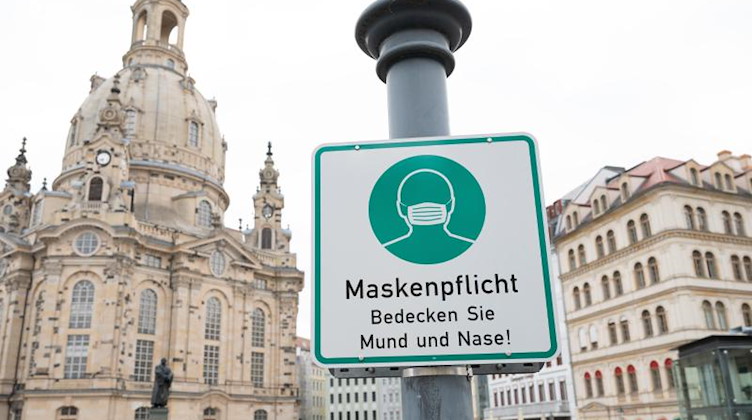 Ein Hinweisschild auf die Maskenpflicht hängt auf dem Neumarkt vor der Frauenkirche. Foto: Sebastian Kahnert/dpa-Zentralbild/dpa/Archivbild