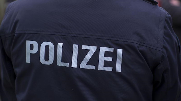 «Polizei» steht auf der Uniform eines Polizisten. Foto: Jens Büttner/zb/dpa/Symbolbild