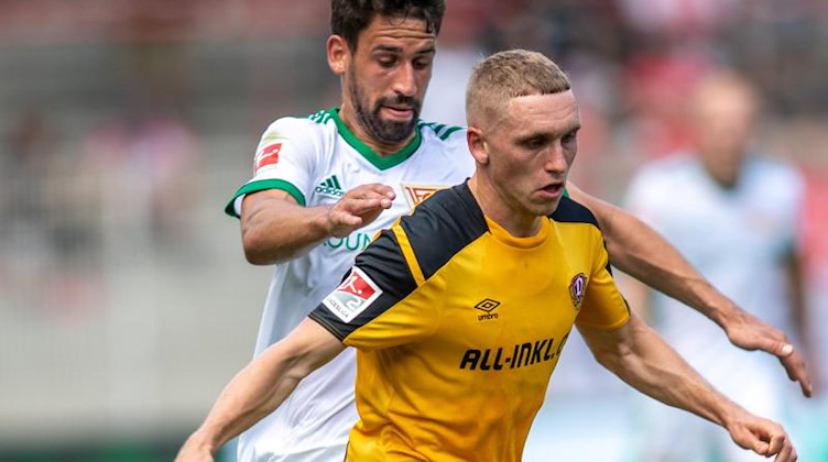 Luca Herrmann von Dynamo Dresden kämpft gegen Berlins Rani Khedira (l) um den Ball. Foto: Andreas Gora/dpa