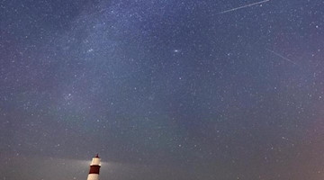 Eine Sternschnuppe ist am Sternenhimmel über dem Leuchtturm zu sehen. Foto: Joe Giddens/PA Wire/dpa