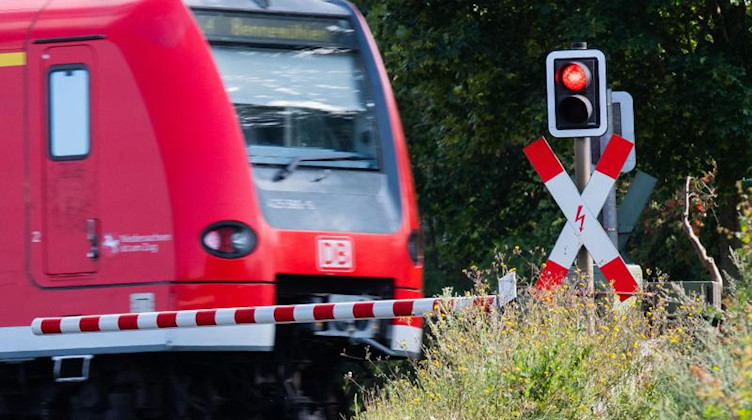 Eine S-Bahn der Deutschen Bahn (DB) fährt an einem Bahnübergang mit einer roten Ampel vorbei. Foto: Julian Stratenschulte/dpa