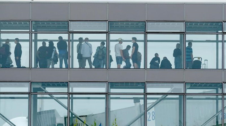 Passagiere stehen am Flughafen Leipzig-Halle in einem Wartebereich. Foto: Sebastian Willnow/dpa-Zentralbild/dpa/Archivbild