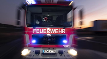 Ein Feuerwehrfahrzeug steht mit eingeschaltetem Blaulicht auf einer Straße. Foto: Patrick Seeger/dpa/Symbolbild