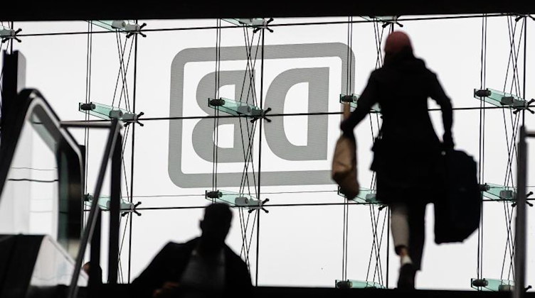 Fahrgäste sind am Berliner Hauptbahnhof vor dem DB-Logo zu sehen. Foto: Christoph Soeder/dpa/Symbolbild