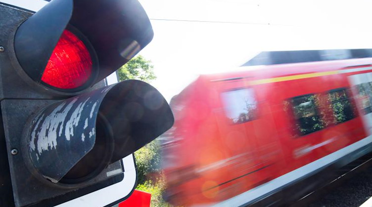 Eine S-Bahn der Deutschen Bahn (DB) fährt an einem Bahnübergang mit einer roten Ampel vorbei. Foto: Julian Stratenschulte/dpa/Archivbild