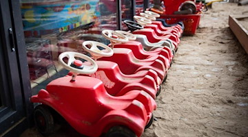 Mehrere Bobbycars stehen auf dem Spielplatz einer Kita. Foto: Christian Charisius/dpa/Symbolbild