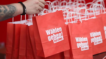 Ein Mann greift beim Start der Linken-Wahlkampfveranstaltungen nach einer Papiertüte mit Wahlwerbung. Foto: Danny Gohlke/dpa