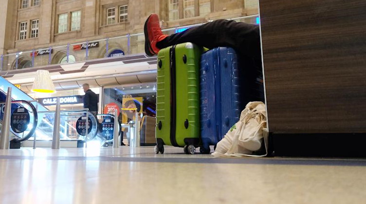 Ein Passagier legt am Leipziger Hauptbahnhof seine Beine auf seine Koffer. Foto: Sebastian Willnow/dpa-Zentralbild/dpa