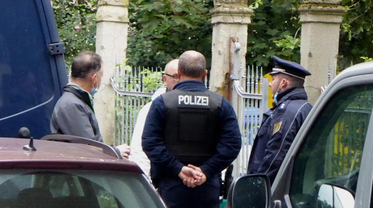 Polizeibeamte unterhalten sich vor dem Wohnhaus, in dem Mutter und Kind getötet wurden. Foto: Mike Müller/TNN/dpa