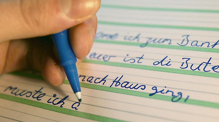 Ein Analphabet schreibt Sätze zur Übung in ein Schulheft. Foto: Oliver Berg/dpa/Symbolbild