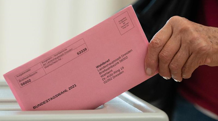 Eine Frau wirft in einem Briefwahlbüro im Bürgersaal des Stadthauses ihren Wahlschein in eine Wahlurne. Foto: Sebastian Kahnert/dpa-Zentralbild/dpa
