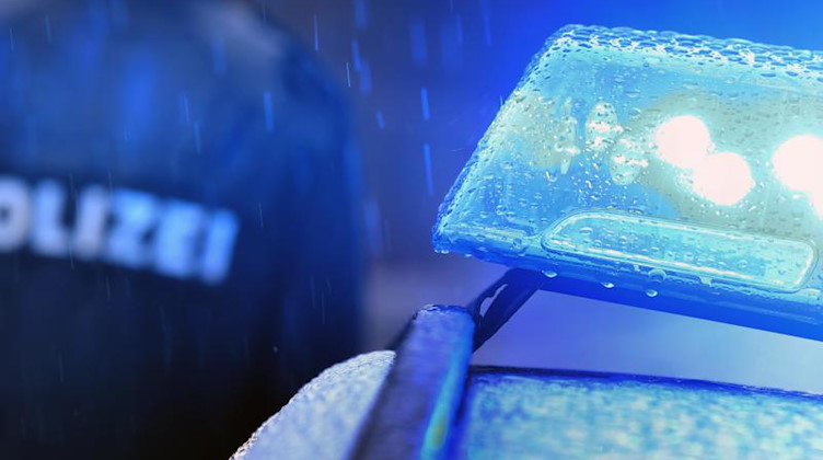 Ein Polizist steht vor einem Streifenwagen mit Blaulicht. Foto: Karl-Josef Hildenbrand/dpa/Symbolbild