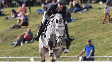 Eine Reiterin ist mit ihrem Hengst auf dem Springparcours unterwegs. Foto: Matthias Rietschel/dpa-Zentralbild/ZB/Archivbild