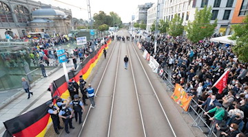 Gegendemonstranten (r) stehen während einer Kundgebung der islam- und fremdenfeindlichen Pegida-Bewegung (l) auf dem Wiener Platz vor dem Hauptbahnhof. Foto: Sebastian Kahnert/dpa-Zentralbild/dpa