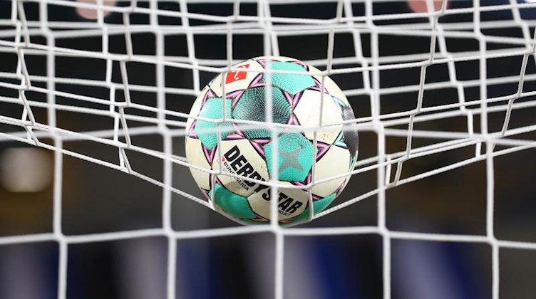 Ein Fußball liegt vor der Partie im Netz. Foto: Friso Gentsch/dpa/Symbolbild