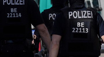Berliner Polizisten gehen über eine Straße. Foto: Paul Zinken/dpa/Symbolbild