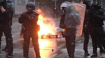 Polizisten stehen an einer brennenden Barrikade im Stadtteil Connewitz. Foto: Sebastian Willnow/dpa-Zentralbild/dpa