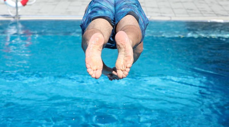 Ein Mann springt von einem Sprungbrett kopfüber ins Wasser. Foto: Thomas Warnack/dpa/Archivbild