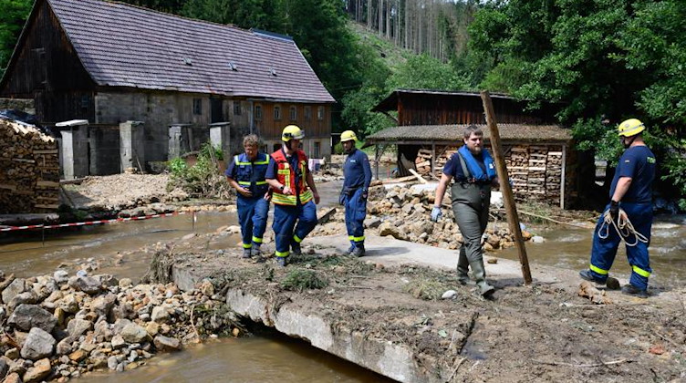 Einsatzkräfte Technisches Hilfswerk beseitigen am Krippenbach im Juli Geröll. Foto: Robert Michael/dpa-Zentralbild/dpa