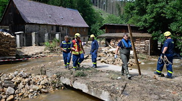 Einsatzkräfte Technisches Hilfswerk beseitigen am Krippenbach im Juli Geröll. Foto: Robert Michael/dpa-Zentralbild/dpa