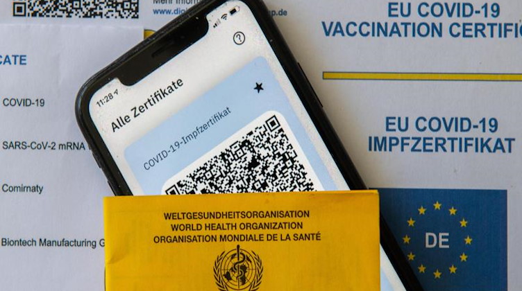 Ein Impfpass und ein Smartphone mit der CovPass-App liegen auf einem Impfzertifikat. Foto: Stefan Puchner/dpa/Symbolbild