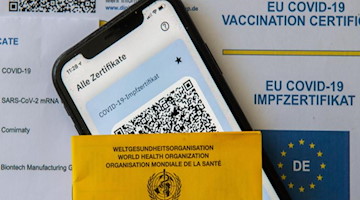 Ein Impfpass und ein Smartphone mit der CovPass-App liegen auf einem Impfzertifikat. Foto: Stefan Puchner/dpa/Symbolbild
