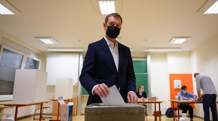 Sachsens Ministerpräsident Michael Kretschmer (CDU) wirft im Wahllokal seinen Stimmzettel in eine Wahlurne. Foto: Robert Michael/dpa-Zentralbild/dpa