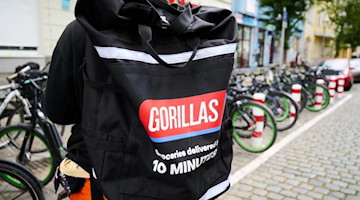 Ein Beschäftigter des Lieferdienstes Gorillas trägt einen Rucksack und steht vor den Fahrrädern. Foto: Annette Riedl/dpa/Archiv