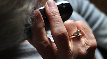 Eine Rentnerin hält ein Telefon ans Ohr. Foto: Karl-Josef Hildenbrand/dpa/Symbolbild
